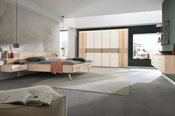 Modernes Schlafzimmer mit schwebendem Massivholzbett, großem Kleiderschrank in Holz und Creme, Schubladenkommode und natürlichem Farbkonzept. Helle, zeitlose Einrichtung für mehr Ruhe, Stil und Stauraum im Schlafzimmer.